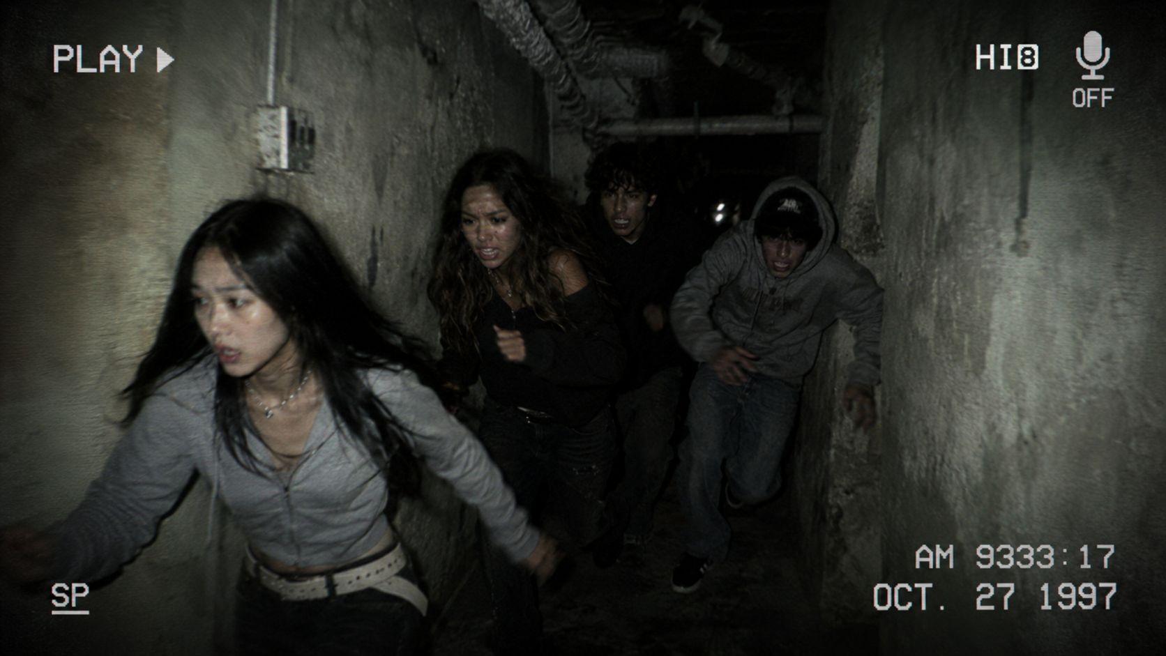 Characters running through an underground corridor
